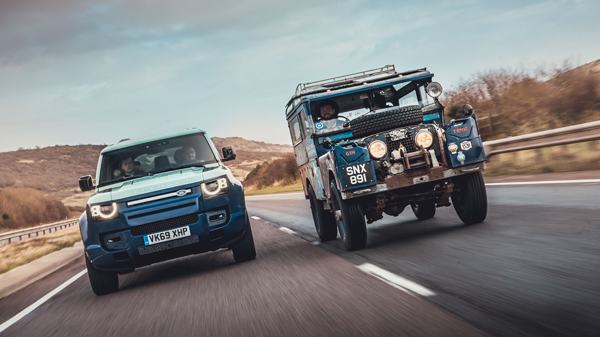Close-up of a new and old LandRover model from behind on the highway